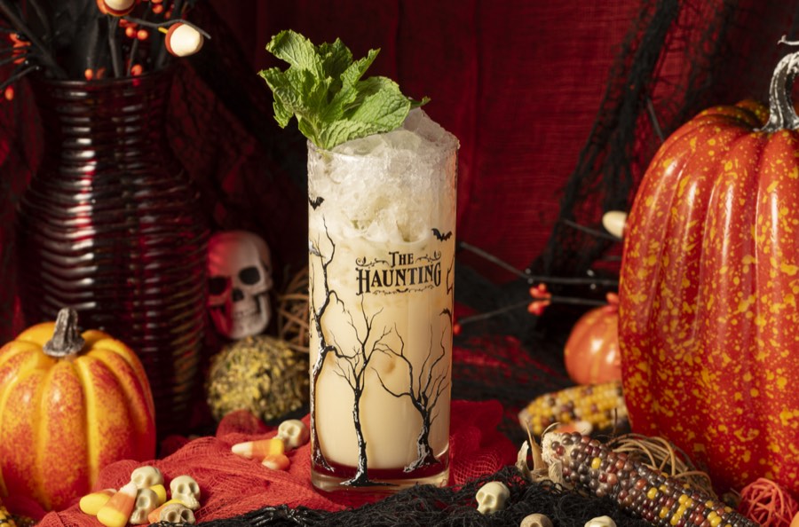 Tall mint-green collins cocktails surrounded by pumpkins and autumn leaves.
