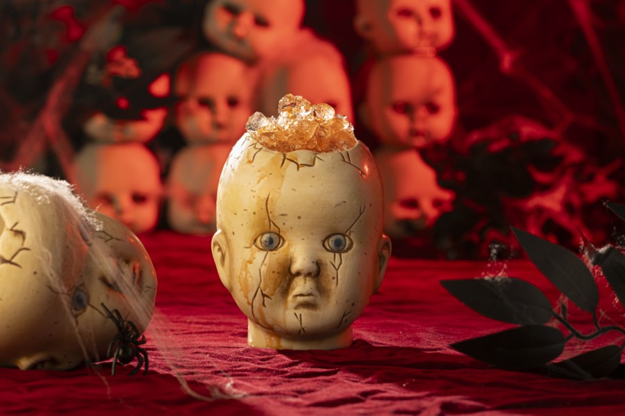 A doll-head mug filled with cocktail, lit in deep red.